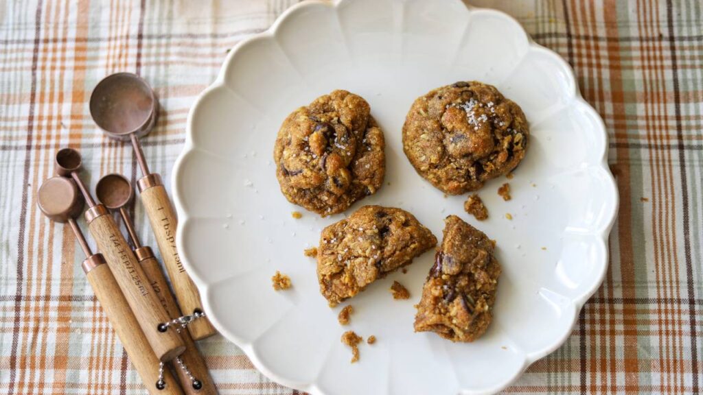 Pumpkin coconut chocolate chip cookies with a bite taken out on a white plate