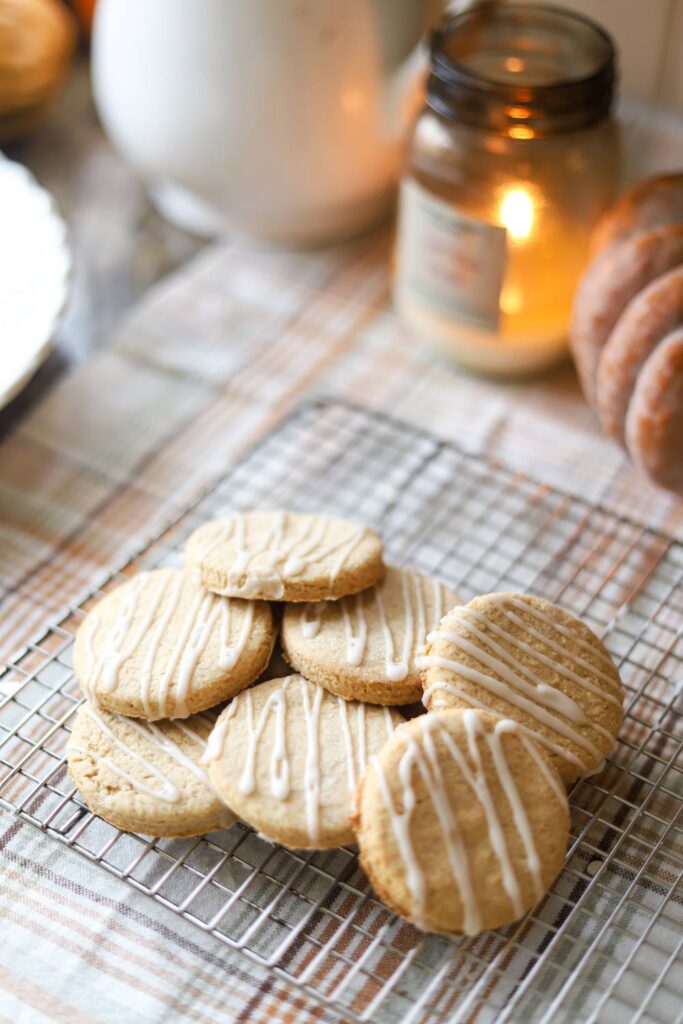 Stacked whole grain sugar cookies with icing drizzle on a cooling rack
