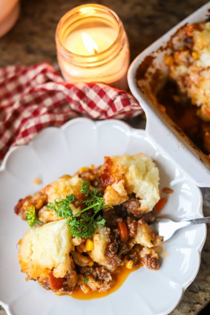 Serving of homemade shepherd’s pie on a white plate with parsley garnish