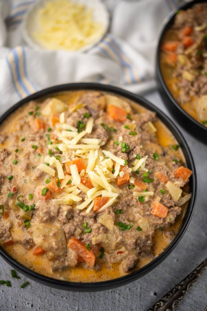 Bowl of healthy cheeseburger soup topped with shredded cheese and chives