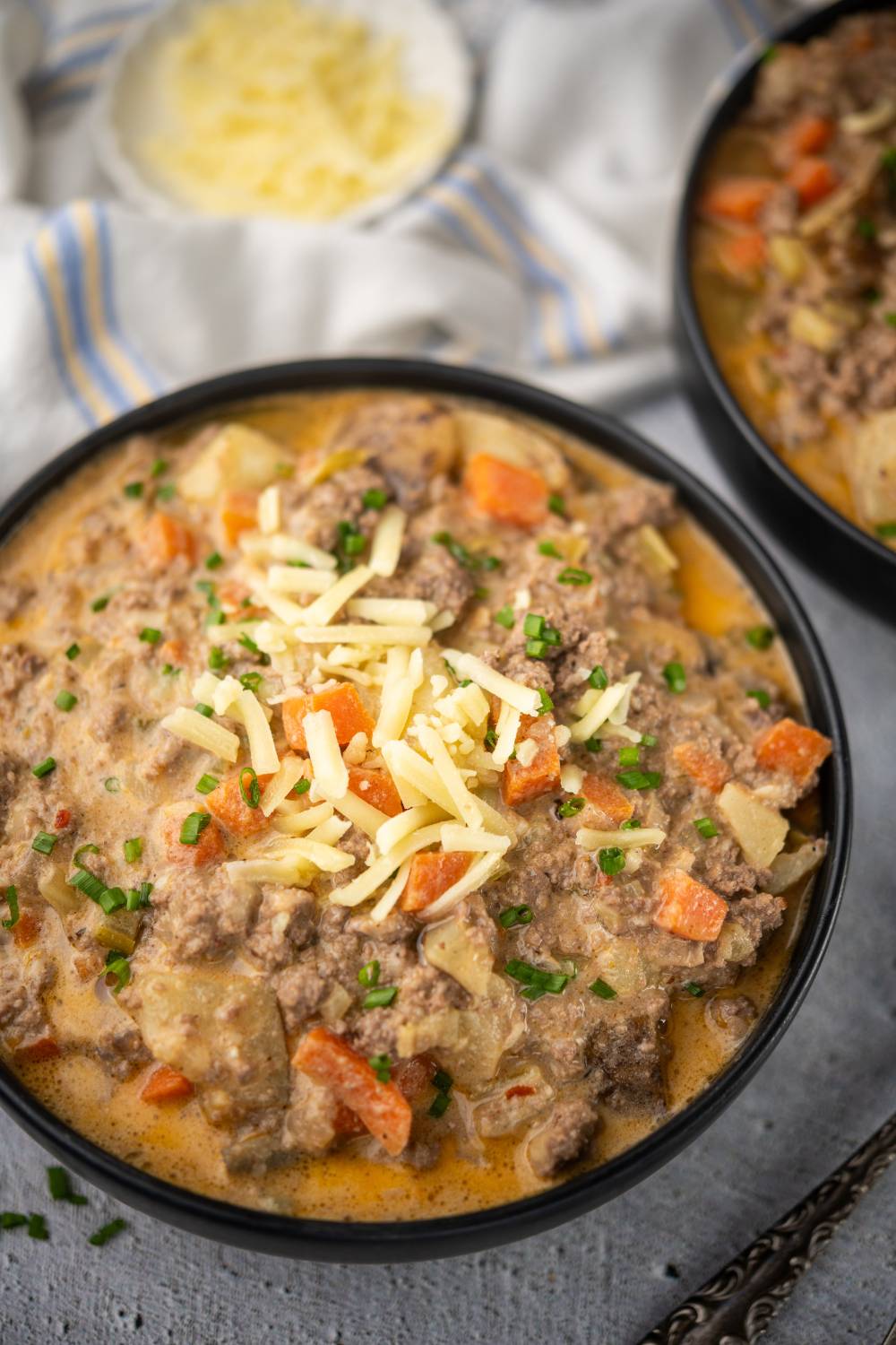 Bowl of healthy cheeseburger soup topped with shredded cheese and chives