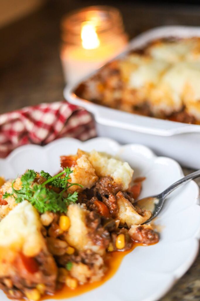 Serving of homemade shepherd’s pie with mashed potatoes, ground beef, and vegetables on a white plate