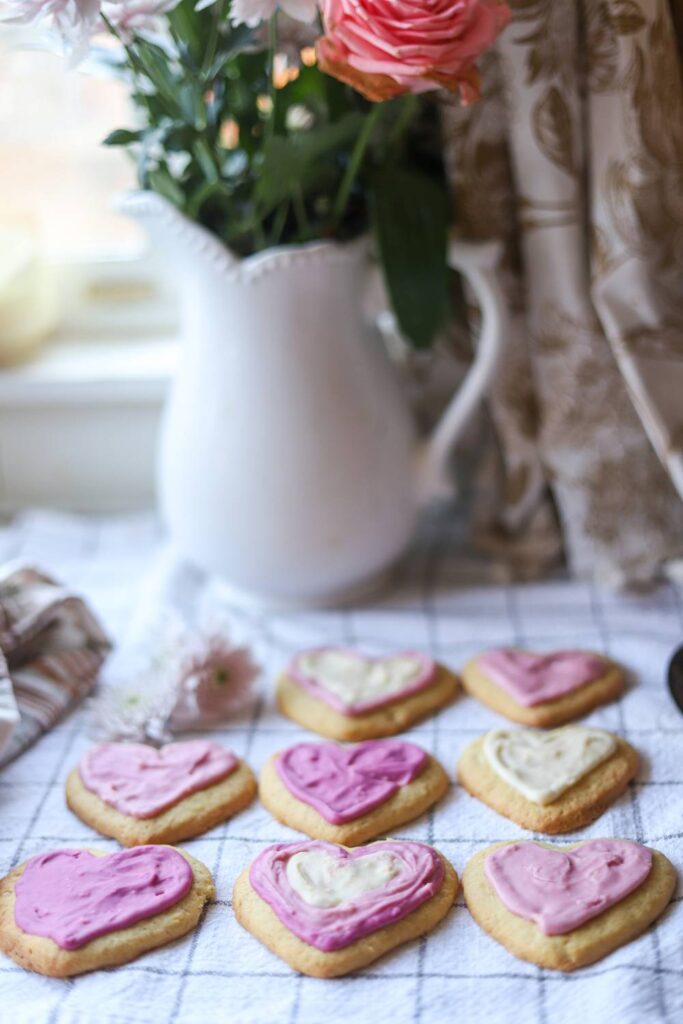 Heart-shaped einkorn lemon sugar cookies with pink and white icing on a kitchen towel