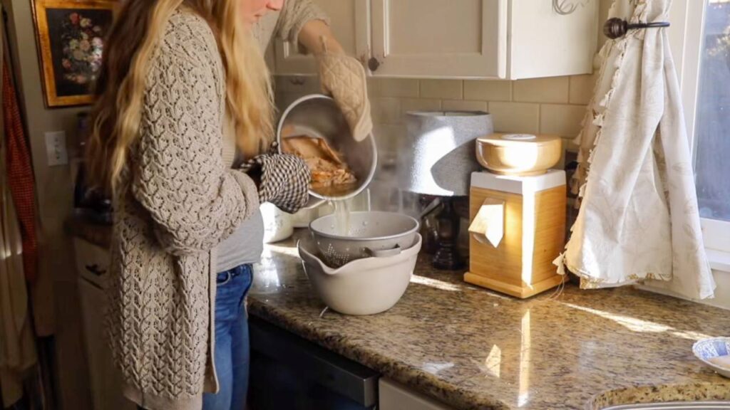 Pouring cooked meat into a strainer over a bowl