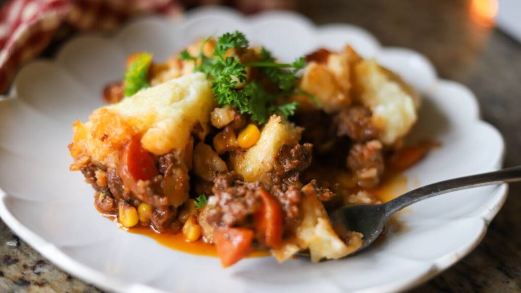 Fork cutting into hearty shepherd’s pie with ground beef and vegetables