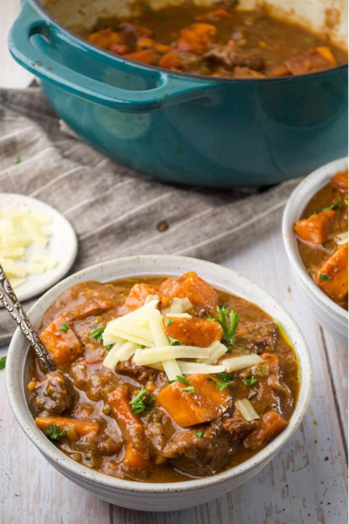 Bowl of sweet and spicy pumpkin beef stew topped with shredded cheese