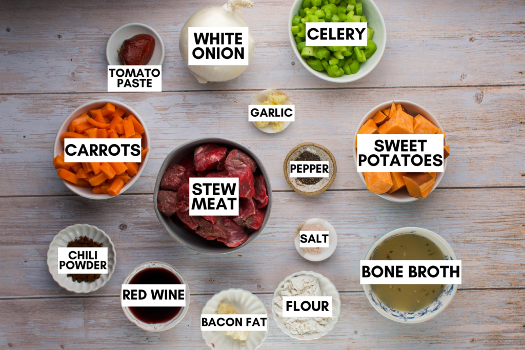 Ingredients for pumpkin beef stew laid out on a white wooden table