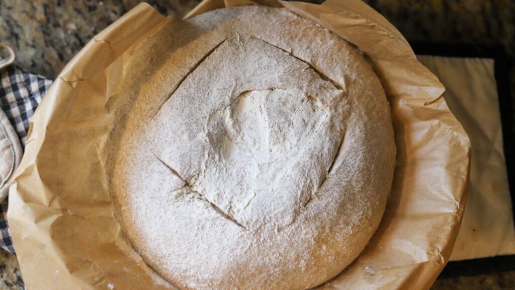 Whole grain sourdough buttermilk bread loaf baked in parchment-lined pan