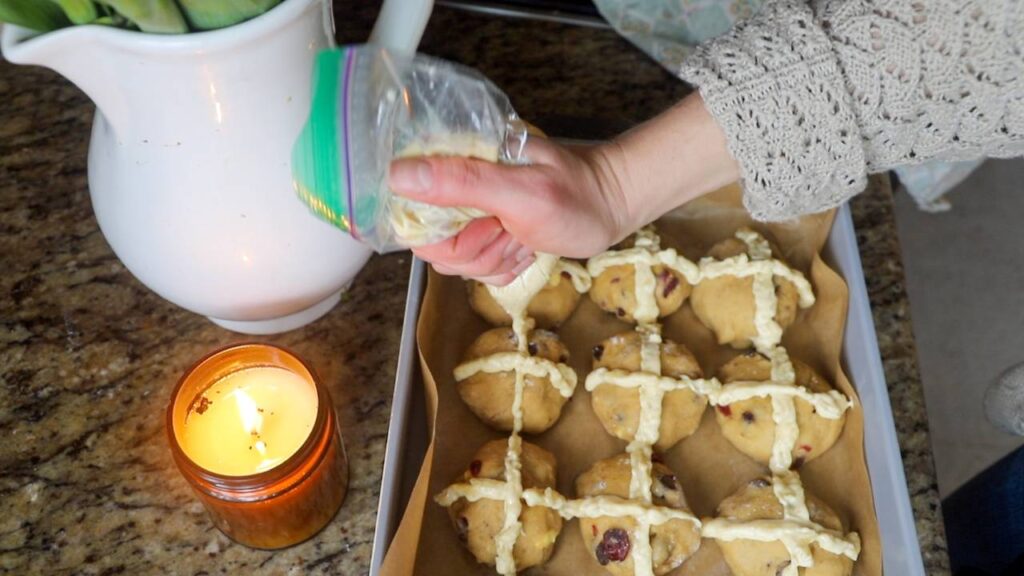 Piping crosses onto sourdough einkorn hot cross buns before baking