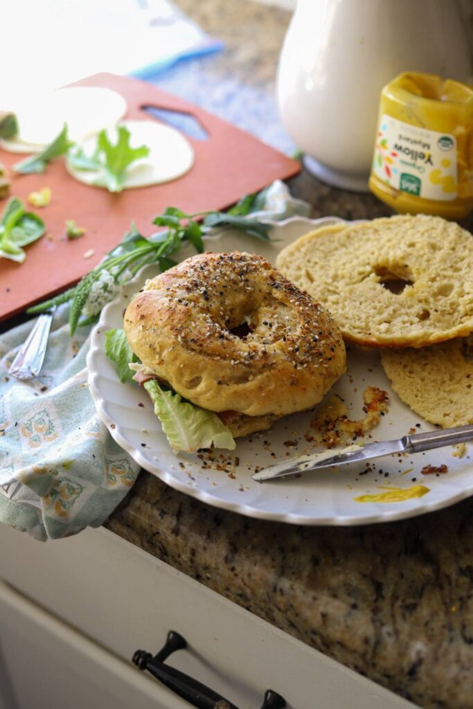 Einkorn sourdough bagel breakfast sandwich on plate with mustard and greens