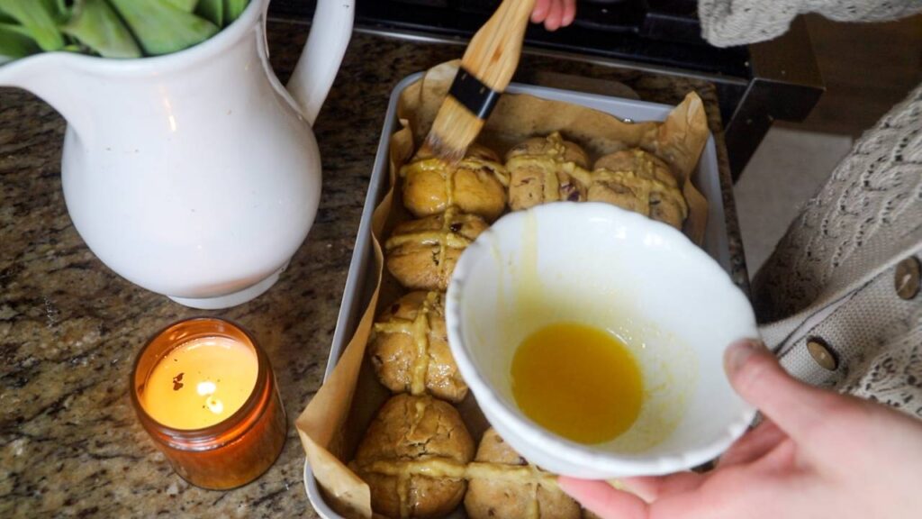 Brushing glaze onto sourdough einkorn hot cross buns