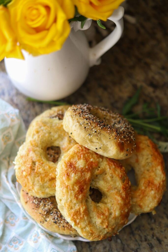 Homemade einkorn sourdough bagels stacked on plate with yellow flowers