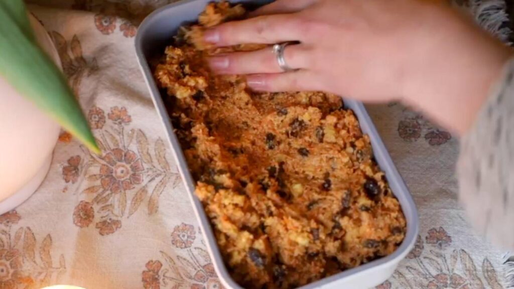 Pressing carrot cake batter into a loaf pan before baking.