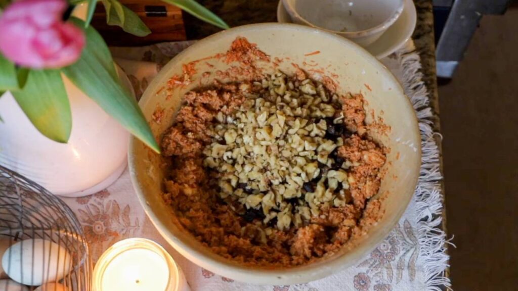 Carrot cake batter in a bowl with raisins and chopped walnuts.