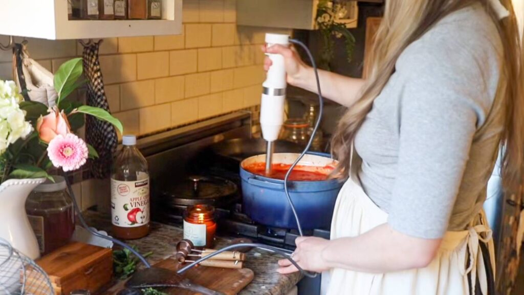 Blending rustic tomato basil pasta sauce in Dutch oven on stove