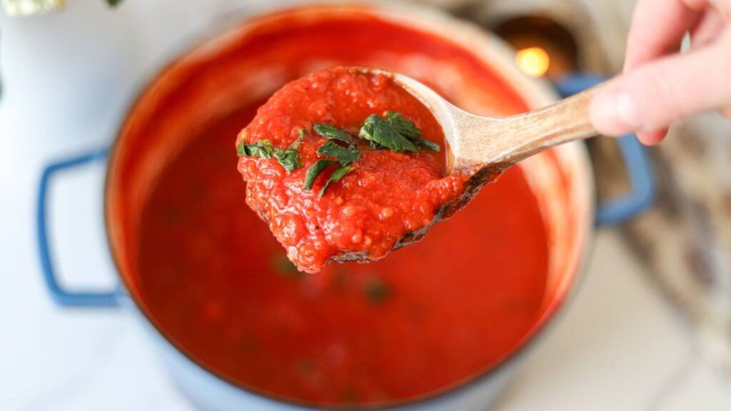 Spoonful of homemade tomato basil pasta sauce over pot