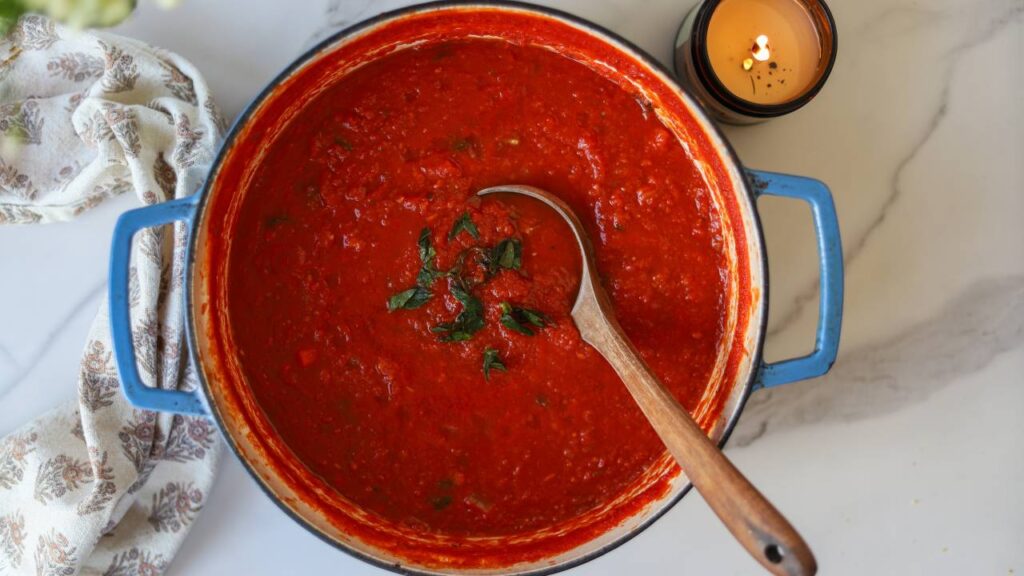 Top view of thick tomato basil pasta sauce with ladle in Dutch oven