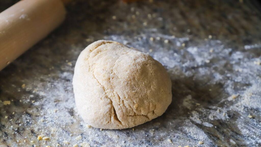 Ball of whole wheat pasta dough on floured counter