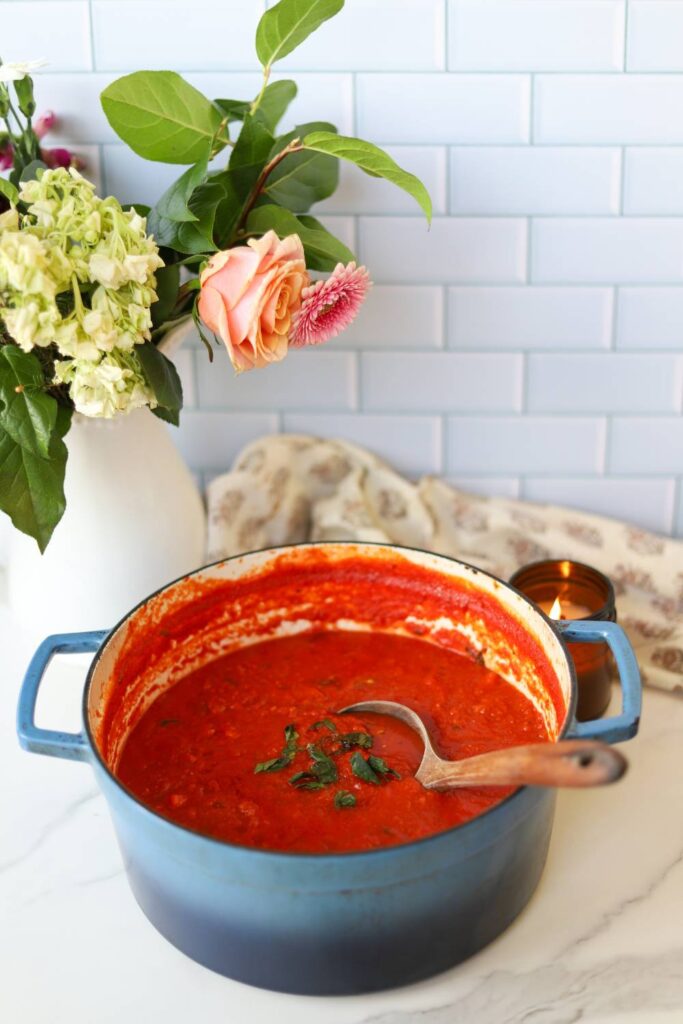 Top view of thick tomato basil pasta sauce with ladle in Dutch oven