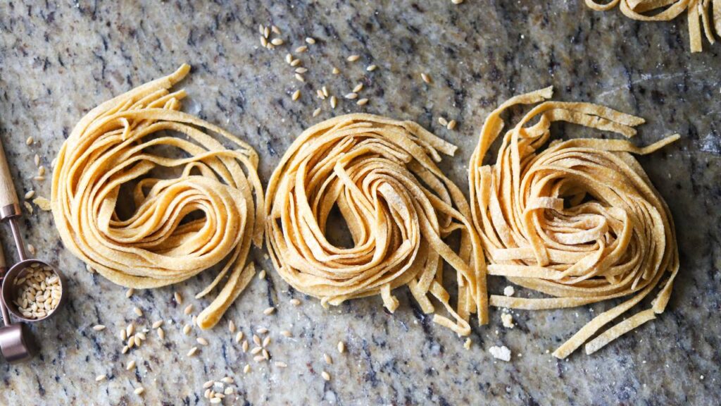 Fresh homemade whole grain pasta nests on marble countertop