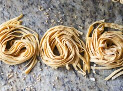 Fresh homemade whole grain pasta nests on marble countertop