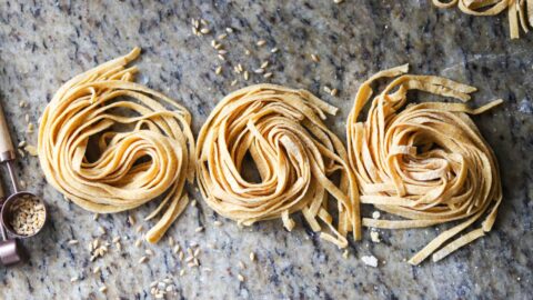 Fresh homemade whole grain pasta nests on marble countertop