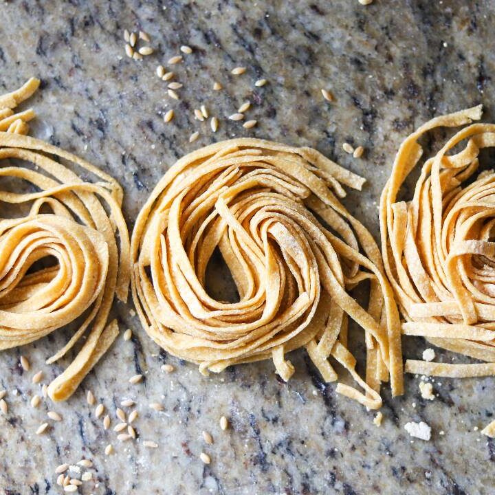 Fresh homemade whole grain pasta nests on marble countertop