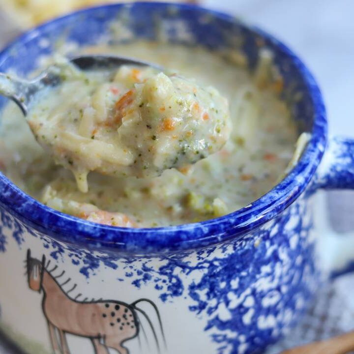 Spoon lifting creamy broccoli cheddar soup from bowl