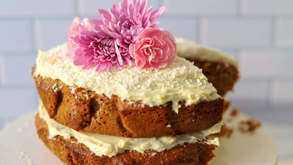 Frosted einkorn coconut almond cake with flowers on top