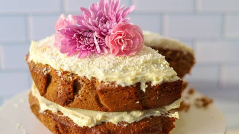 Frosted einkorn coconut almond cake with flowers on top