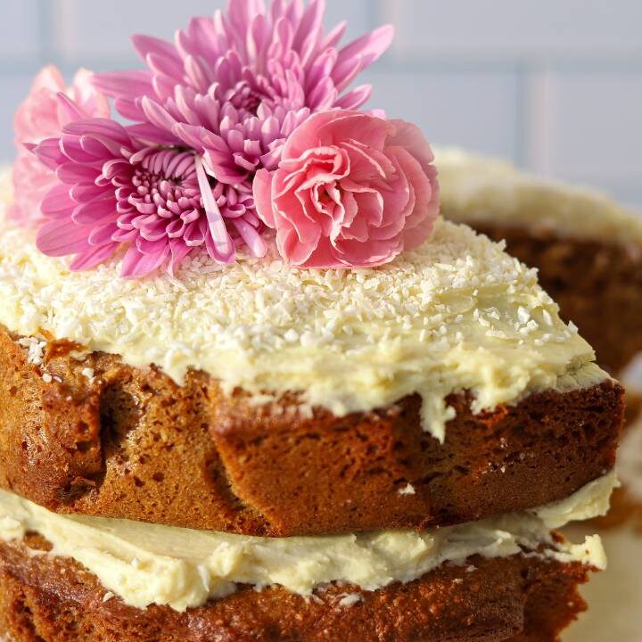 Frosted einkorn coconut almond cake with flowers on top