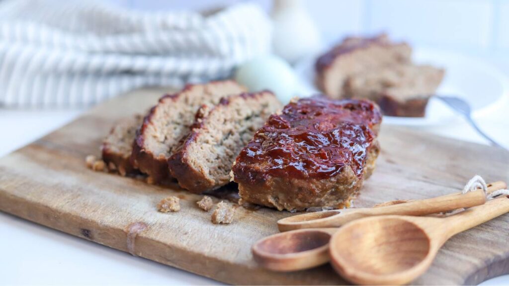 Homemade meatloaf slices on wooden cutting board