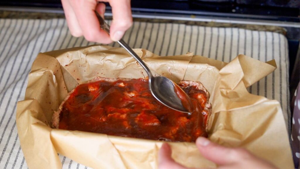 Spreading ketchup glaze on homemade meatloaf
