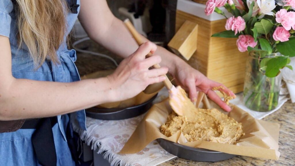 Pressing einkorn cake batter into pan lined with parchment paper