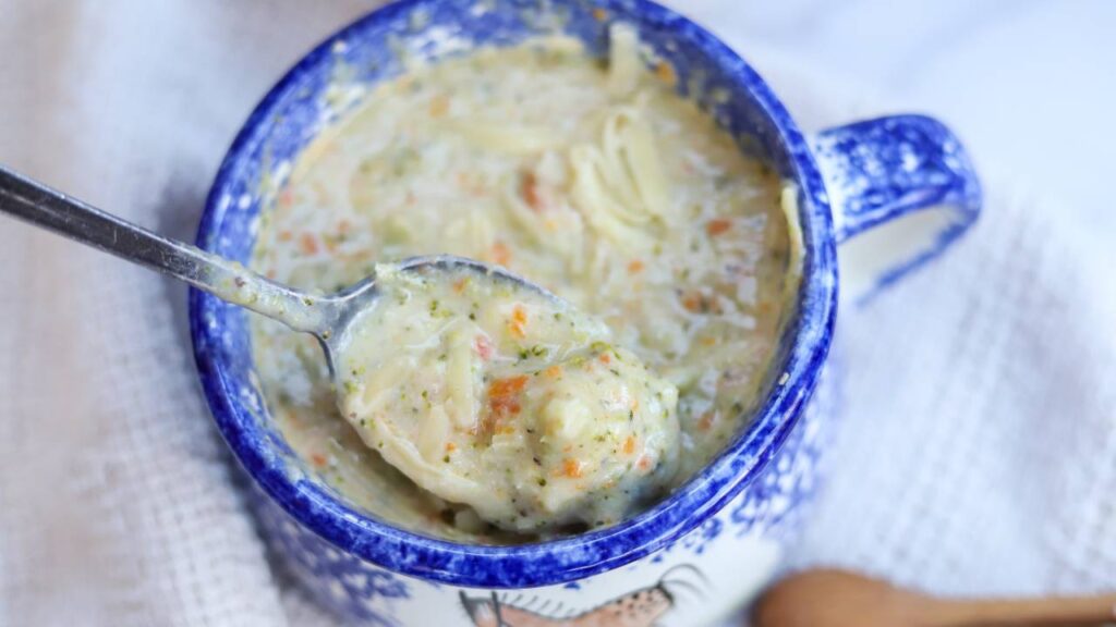 Spoonful of creamy broccoli cheddar soup in blue bowl