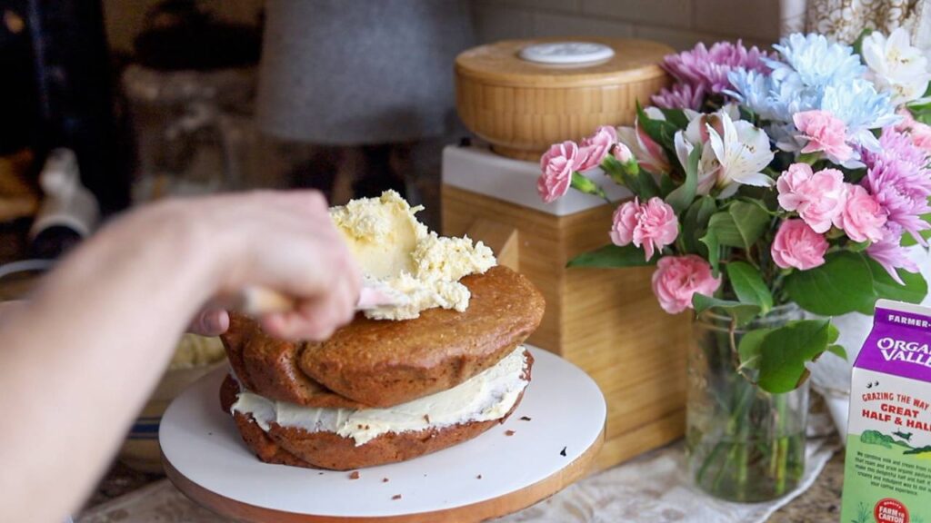 Spreading cream cheese frosting on einkorn cake layers