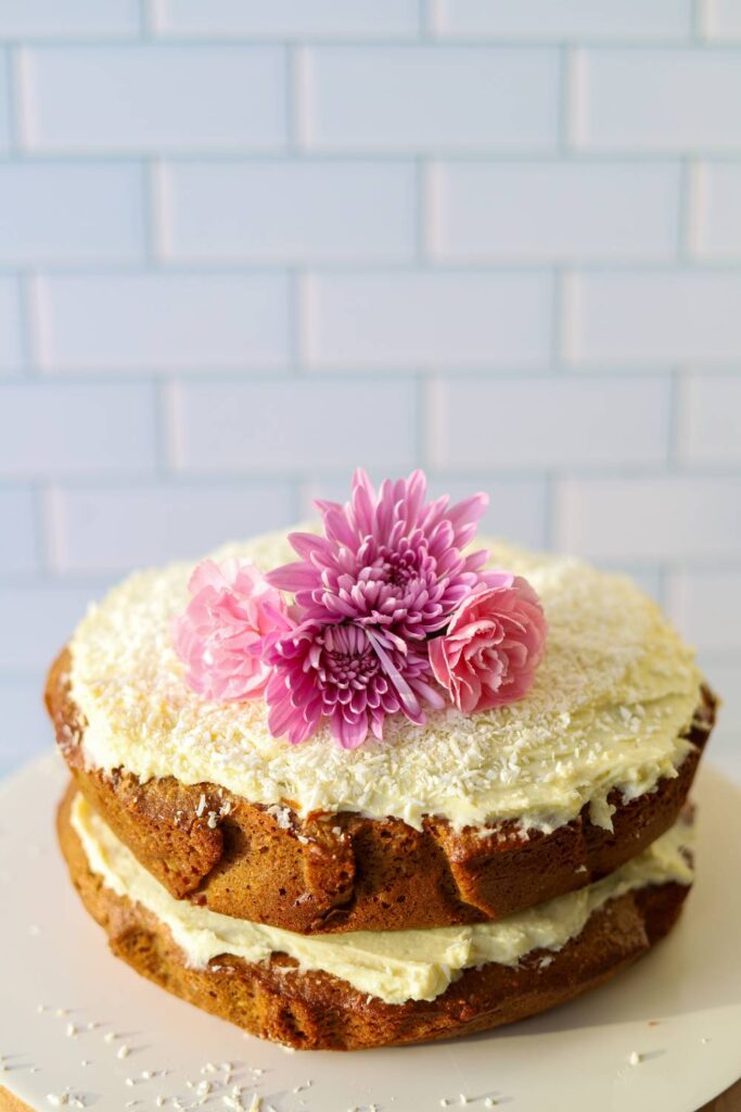 Close up of einkorn coconut almond cake with frosting and flowers