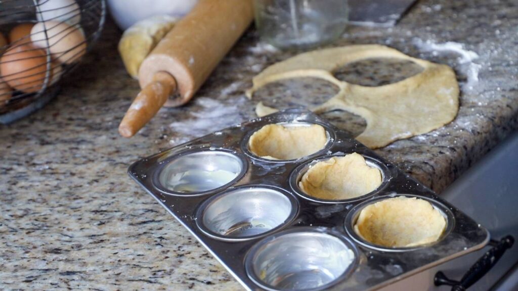 Homemade pie crust pressed into a muffin tin for mini pies
