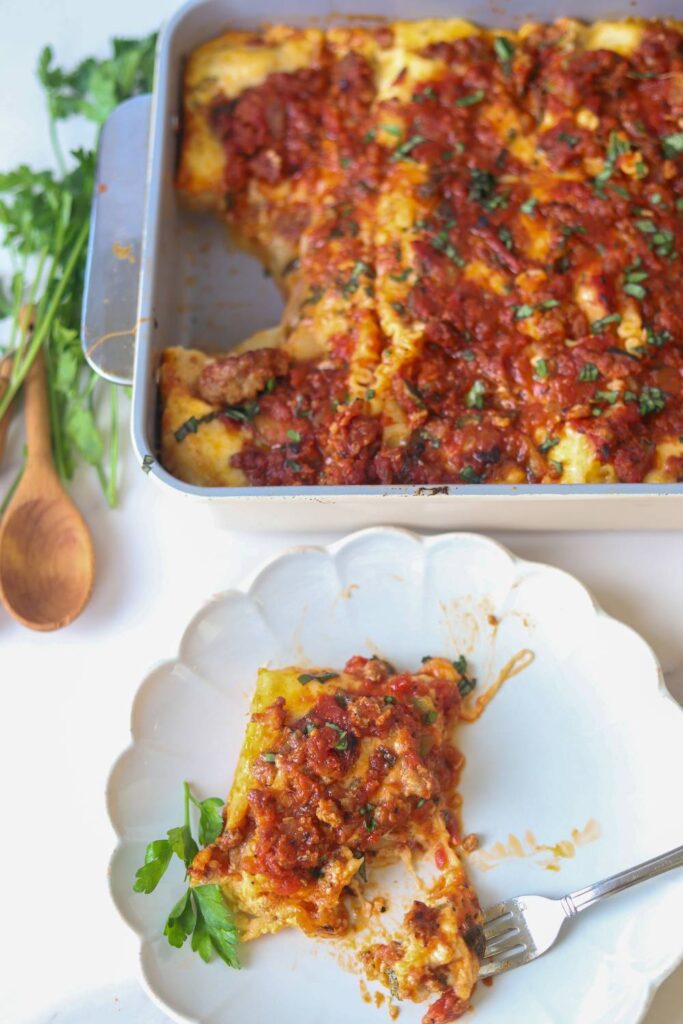 Homemade cottage cheese lasagna served on a plate with the baking dish in the background.