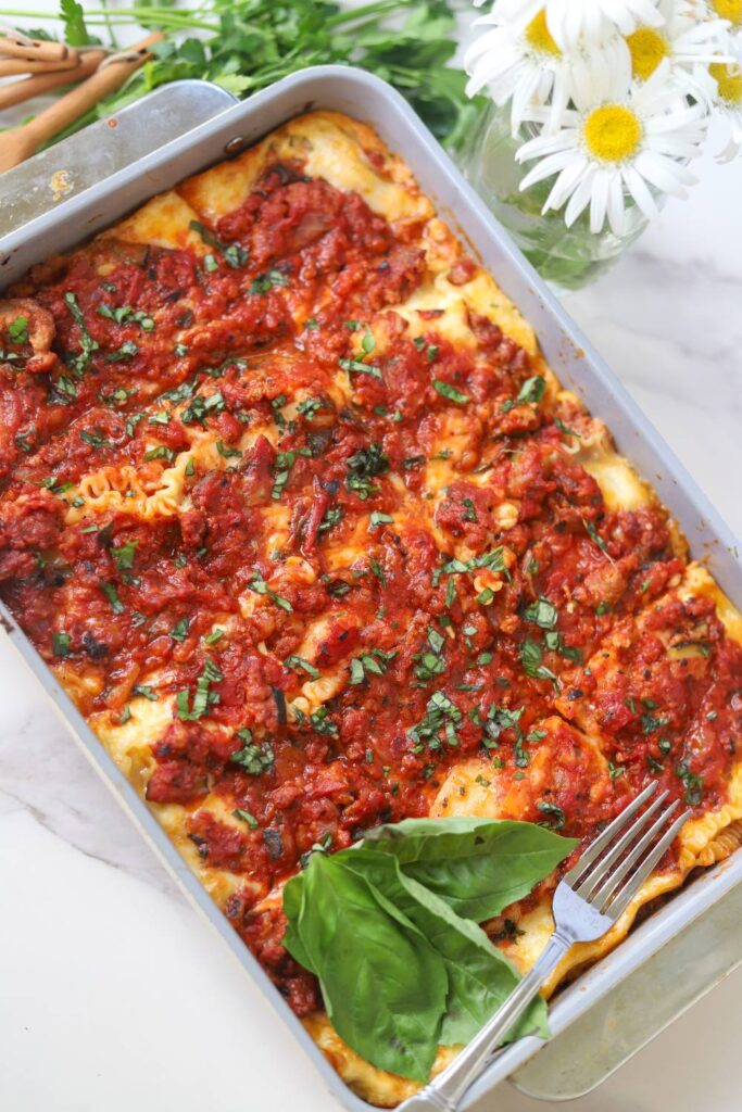 Freshly baked cottage cheese lasagna in a baking dish with basil garnish.