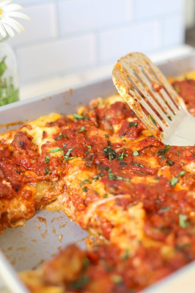 Close-up of homemade cottage cheese lasagna topped with meat sauce and fresh basil.