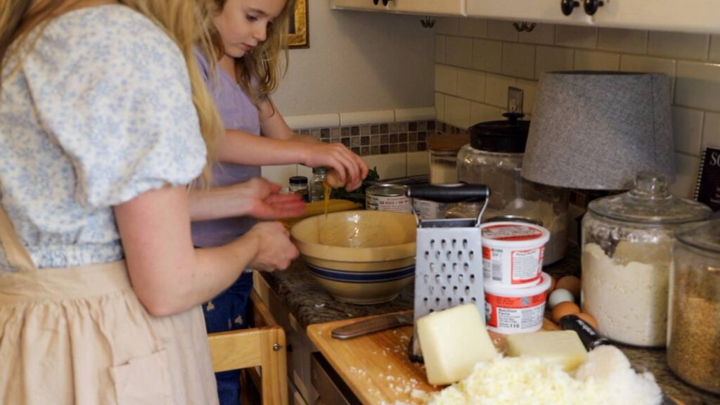Making homemade cottage cheese lasagna with a child helping in the kitchen.