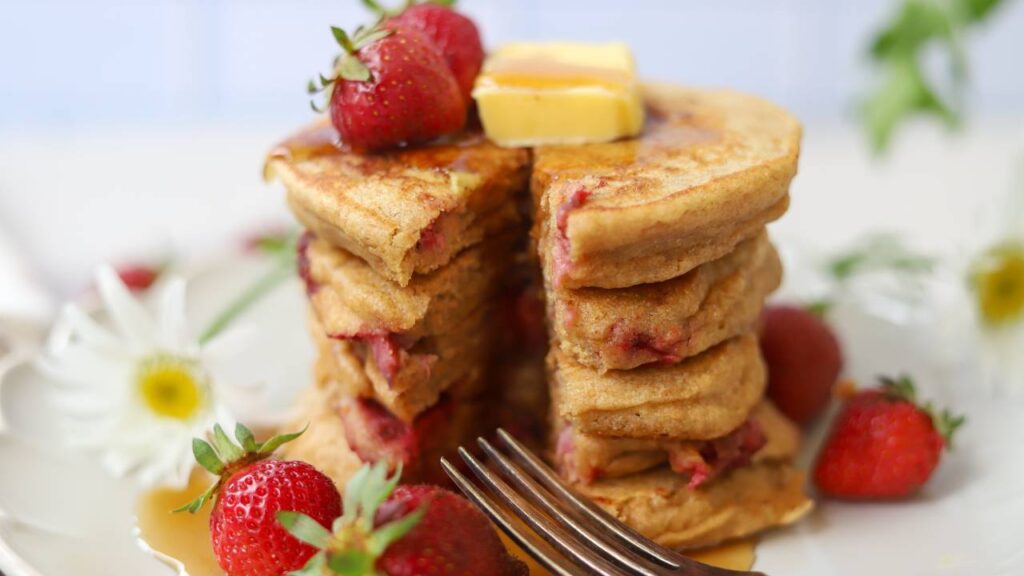 Close-up of whole grain einkorn strawberry pancakes with butter and maple syrup.