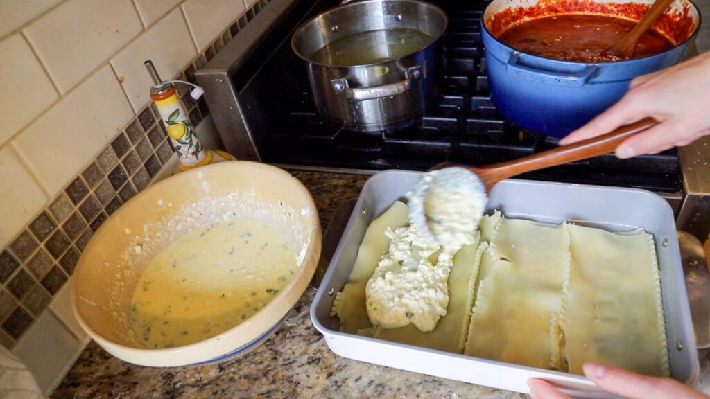 Layering cottage cheese mixture over lasagna noodles in a baking dish.