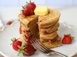 Whole grain einkorn strawberry pancakes served with butter, maple syrup, and fresh strawberries.