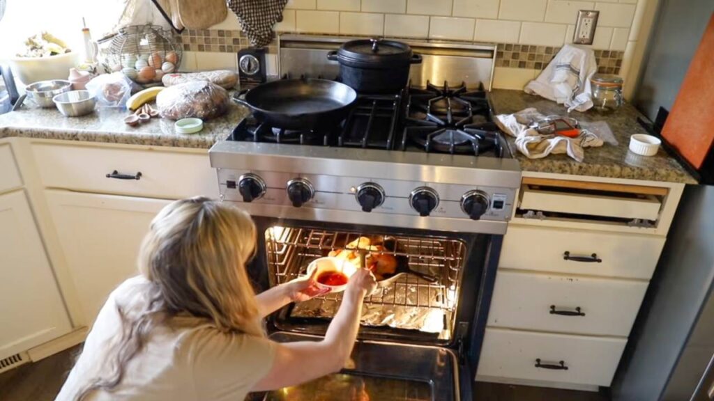 Basting a spatchcock chicken with maple BBQ glaze in the oven.