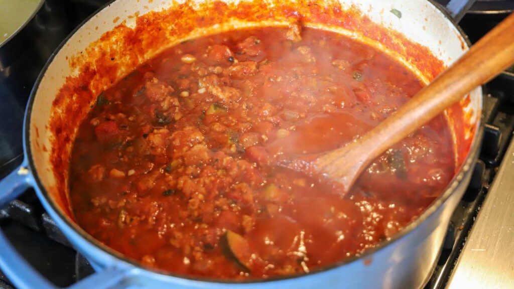 Homemade beef and pork lasagna sauce simmering with tomatoes, zucchini, onions, and herbs.