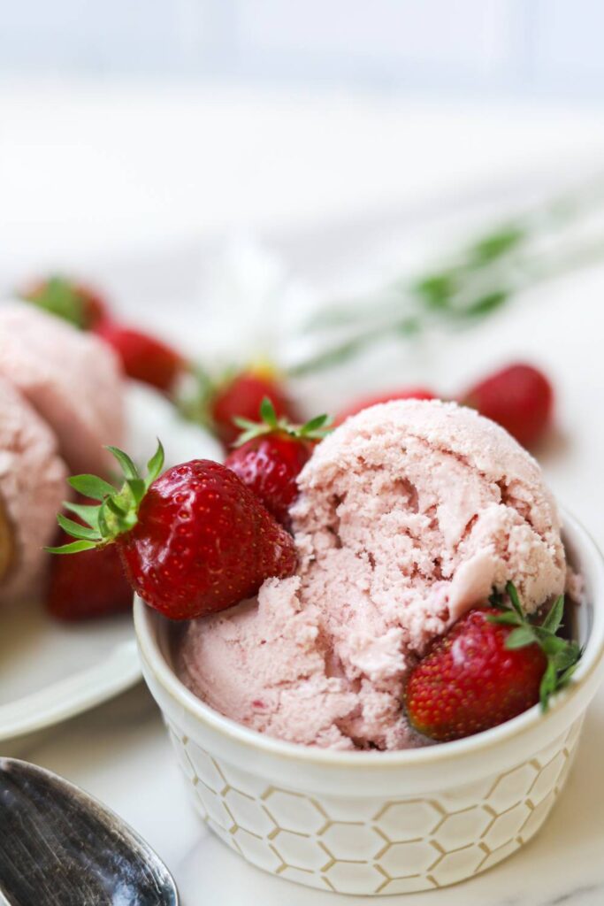 Homemade strawberry ice cream in a bowl with fresh strawberries