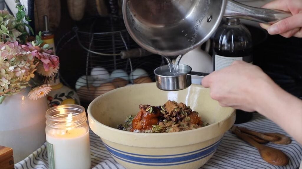 Pumpkin spice granola ingredients being mixed with melted coconut oil