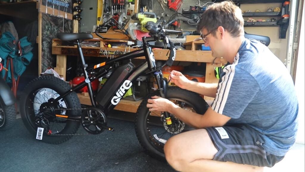 Man assembling the Qlife Racer electric bike in a garage